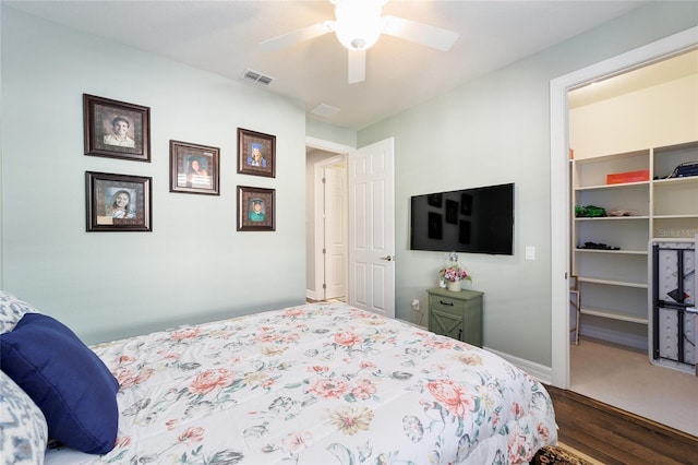 bedroom featuring a spacious closet, a closet, ceiling fan, and hardwood / wood-style flooring