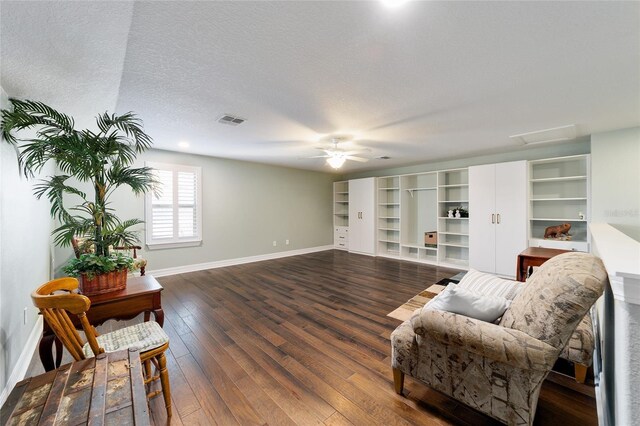 living room featuring ceiling fan, dark hardwood / wood-style flooring, and a textured ceiling