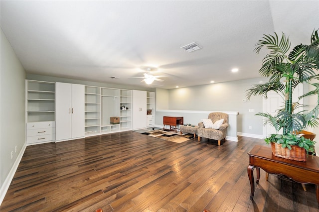 sitting room with ceiling fan and dark wood-type flooring