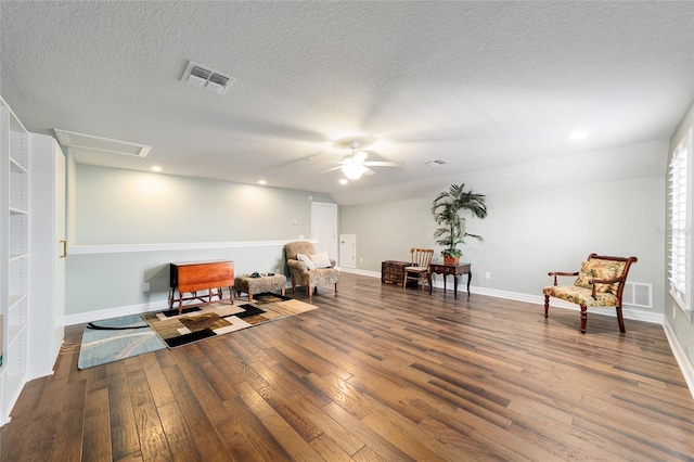 living area featuring hardwood / wood-style flooring, ceiling fan, and a textured ceiling