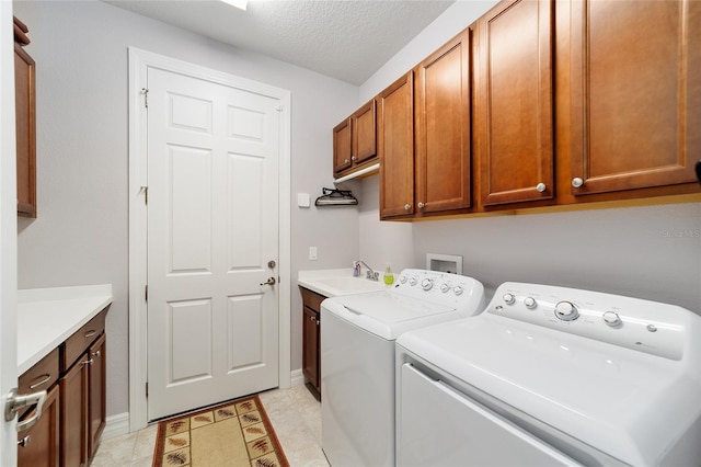 laundry room with cabinets, sink, washing machine and dryer, a textured ceiling, and light tile patterned flooring