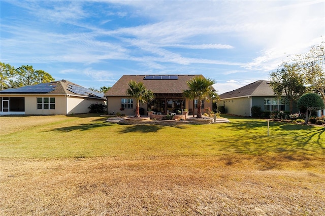 back of property featuring a yard, a patio, and solar panels