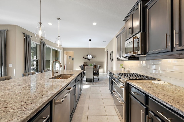 kitchen featuring light stone counters, stainless steel appliances, sink, hanging light fixtures, and light tile patterned flooring