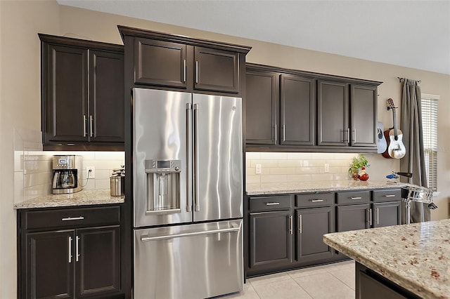 kitchen with tasteful backsplash, stainless steel fridge with ice dispenser, light tile patterned floors, and light stone countertops