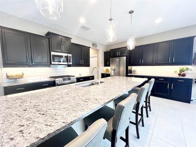 kitchen with backsplash, light stone counters, stainless steel appliances, sink, and decorative light fixtures