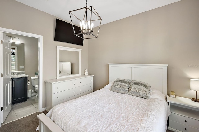 carpeted bedroom featuring an inviting chandelier and ensuite bath