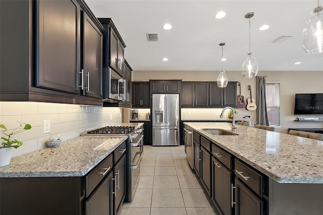 kitchen featuring pendant lighting, stainless steel appliances, a center island with sink, and sink