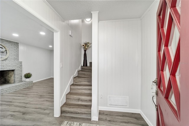 stairway with a fireplace, wood-type flooring, and wood walls