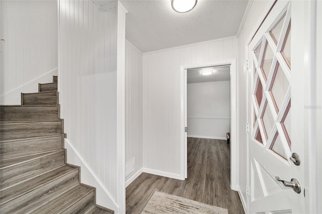 stairway with wooden walls, hardwood / wood-style floors, and a textured ceiling