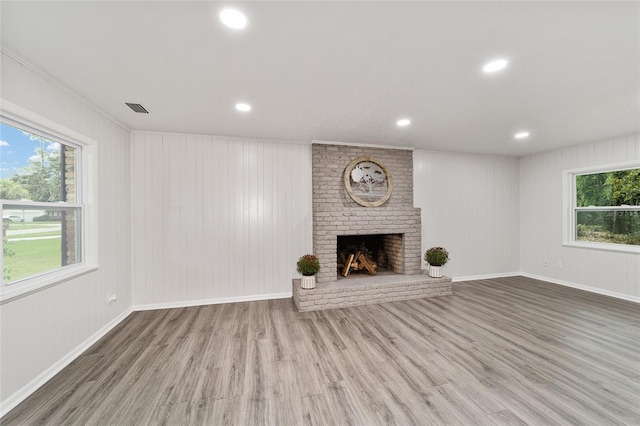 unfurnished living room with plenty of natural light, wood-type flooring, and a brick fireplace