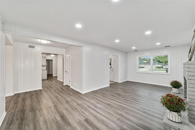 unfurnished living room featuring wood-type flooring and wood walls