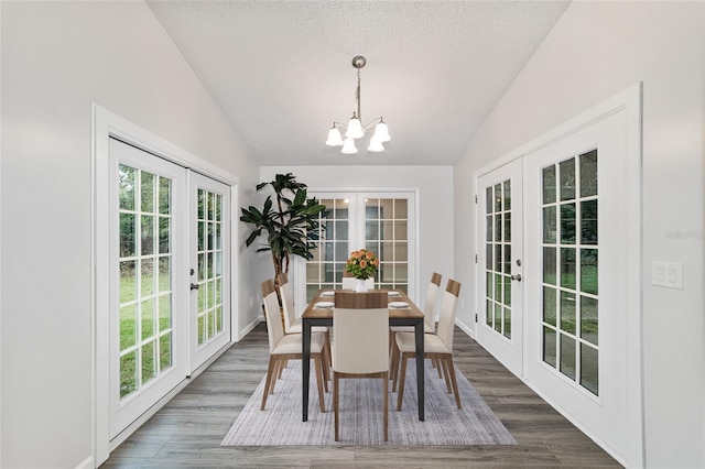 dining room featuring dark hardwood / wood-style floors, an inviting chandelier, lofted ceiling, and french doors