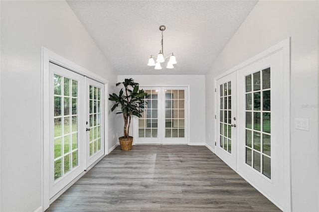 unfurnished sunroom featuring vaulted ceiling, an inviting chandelier, and french doors