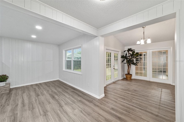 spare room with hardwood / wood-style floors, a notable chandelier, a textured ceiling, and french doors