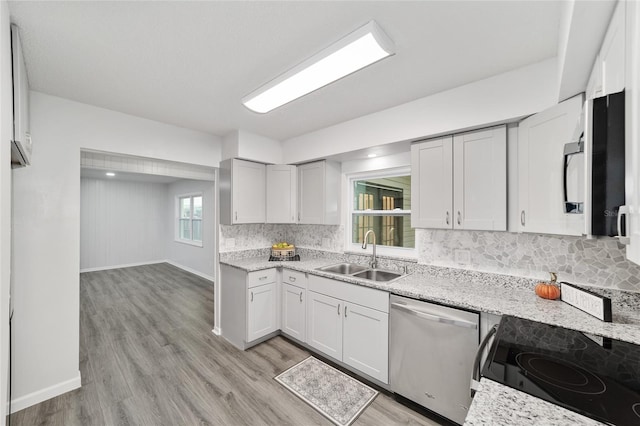 kitchen featuring light stone countertops, sink, stainless steel dishwasher, stove, and light hardwood / wood-style floors