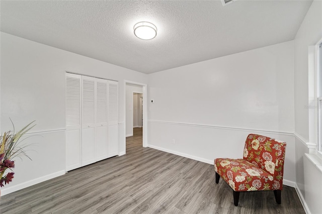 living area featuring a textured ceiling and hardwood / wood-style flooring