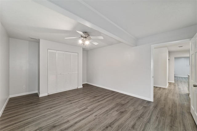 unfurnished bedroom featuring beam ceiling, ceiling fan, a closet, and dark wood-type flooring