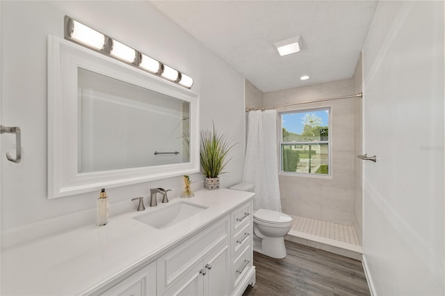 bathroom featuring a shower with shower curtain, hardwood / wood-style floors, vanity, and toilet