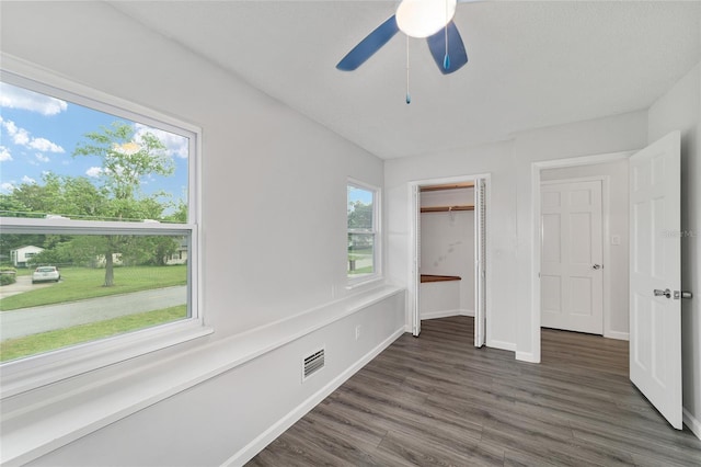 unfurnished bedroom featuring multiple windows, dark wood-type flooring, and ceiling fan