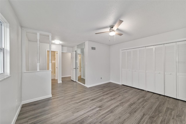 unfurnished bedroom with hardwood / wood-style floors, ceiling fan, and a textured ceiling