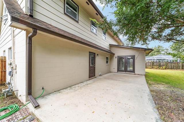 view of property exterior featuring a lawn, french doors, and a patio