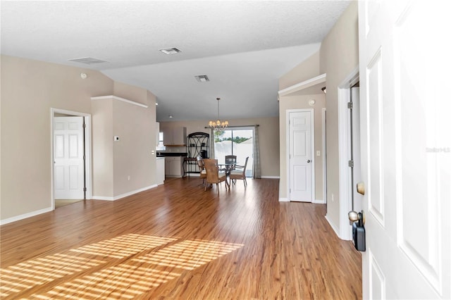 entryway featuring hardwood / wood-style flooring, a textured ceiling, high vaulted ceiling, and a chandelier