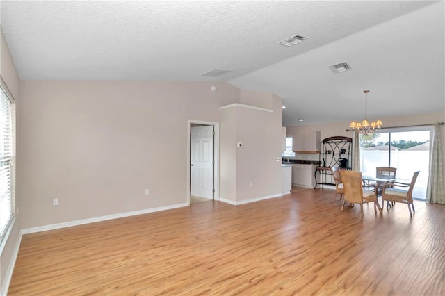 interior space featuring light wood-type flooring, lofted ceiling, a textured ceiling, and an inviting chandelier