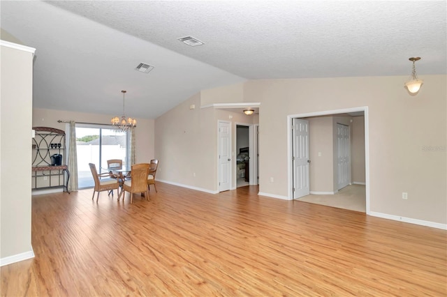 unfurnished dining area featuring a textured ceiling, vaulted ceiling, light hardwood / wood-style flooring, and a notable chandelier