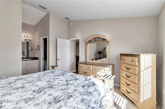 bedroom with ensuite bathroom, lofted ceiling, and sink