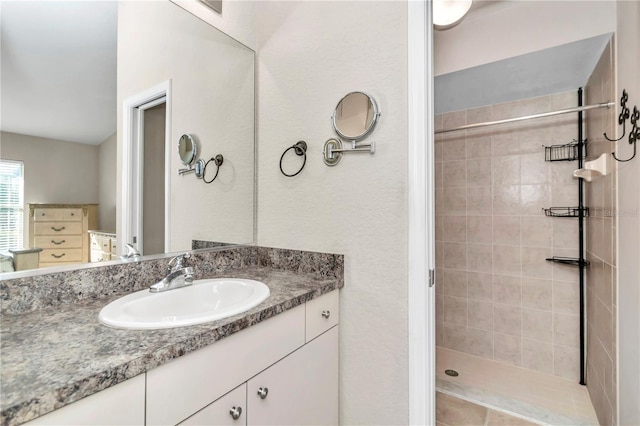 bathroom with a tile shower and vanity