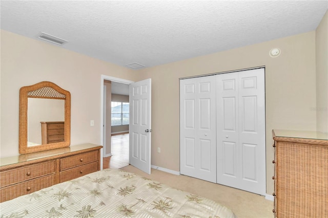 unfurnished bedroom featuring light carpet, a textured ceiling, and a closet