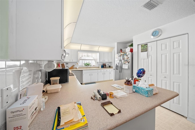 kitchen featuring a textured ceiling, white cabinetry, kitchen peninsula, and appliances with stainless steel finishes