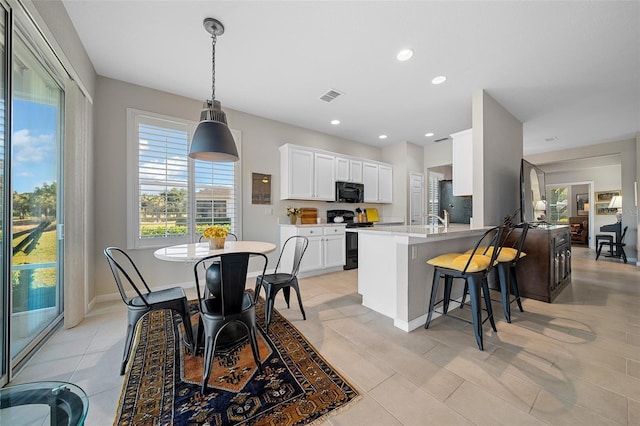 kitchen with white cabinetry, range with electric stovetop, kitchen peninsula, decorative light fixtures, and light tile patterned flooring