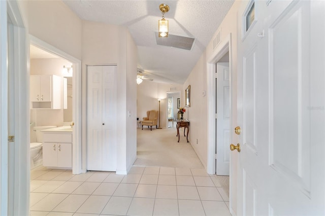 corridor with a textured ceiling and light tile patterned flooring