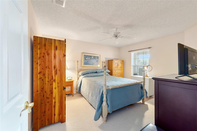 carpeted bedroom featuring ceiling fan and a textured ceiling