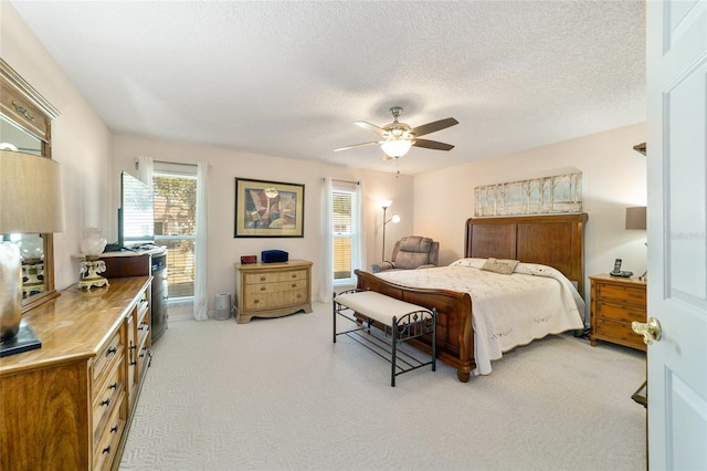 bedroom with light carpet, ceiling fan, and a textured ceiling