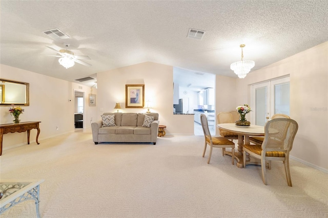 carpeted dining area featuring ceiling fan with notable chandelier, french doors, a textured ceiling, and lofted ceiling