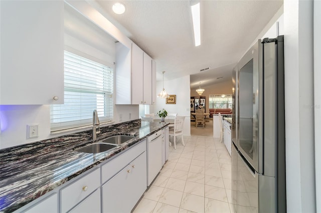 kitchen with dishwasher, lofted ceiling, sink, white cabinetry, and stainless steel refrigerator