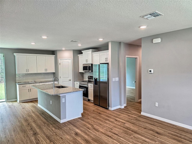 kitchen with dark hardwood / wood-style flooring, stainless steel appliances, sink, a center island with sink, and white cabinets