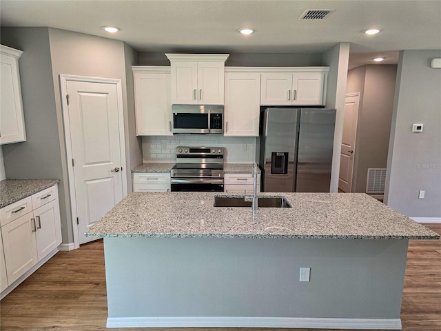 kitchen featuring hardwood / wood-style floors, a center island with sink, sink, white cabinetry, and stainless steel appliances