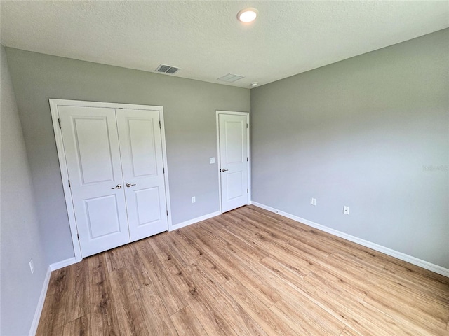 unfurnished bedroom with a closet, light hardwood / wood-style flooring, and a textured ceiling