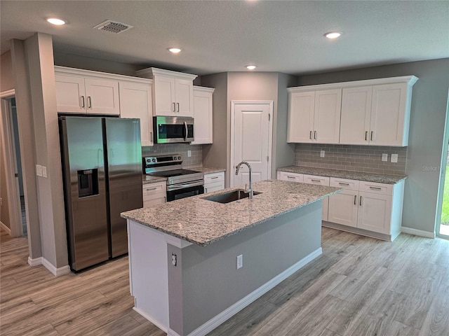 kitchen featuring white cabinets, appliances with stainless steel finishes, light stone counters, and sink