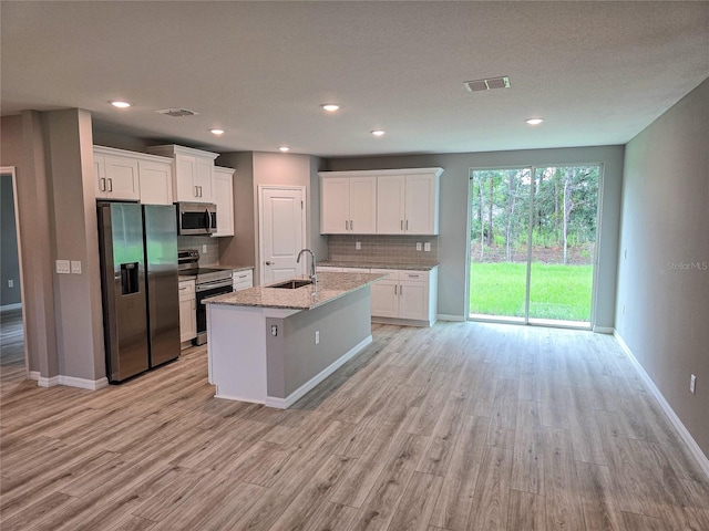 kitchen featuring sink, light stone countertops, an island with sink, white cabinetry, and stainless steel appliances