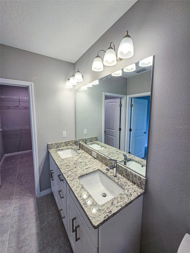 bathroom with tile patterned flooring, vanity, and a textured ceiling