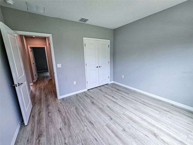 unfurnished bedroom with a closet, light hardwood / wood-style floors, and a textured ceiling