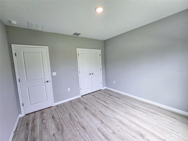 unfurnished bedroom with a closet, a textured ceiling, and light hardwood / wood-style flooring