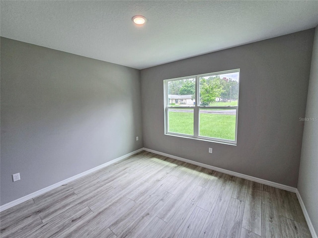 unfurnished room with light hardwood / wood-style floors and a textured ceiling