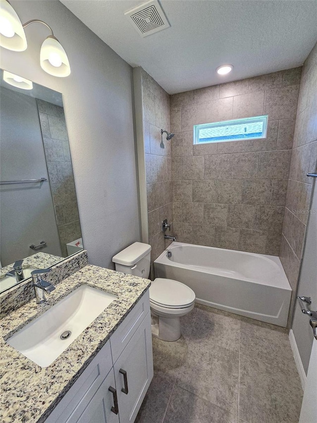 full bathroom with vanity, tile patterned floors, tiled shower / bath, toilet, and a textured ceiling