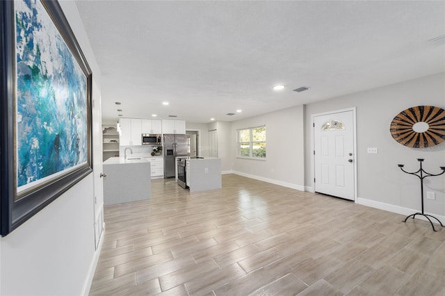 living room with light hardwood / wood-style flooring, a textured ceiling, and sink