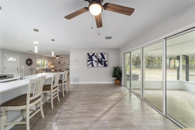 kitchen featuring a kitchen breakfast bar, ceiling fan, a wealth of natural light, and sink